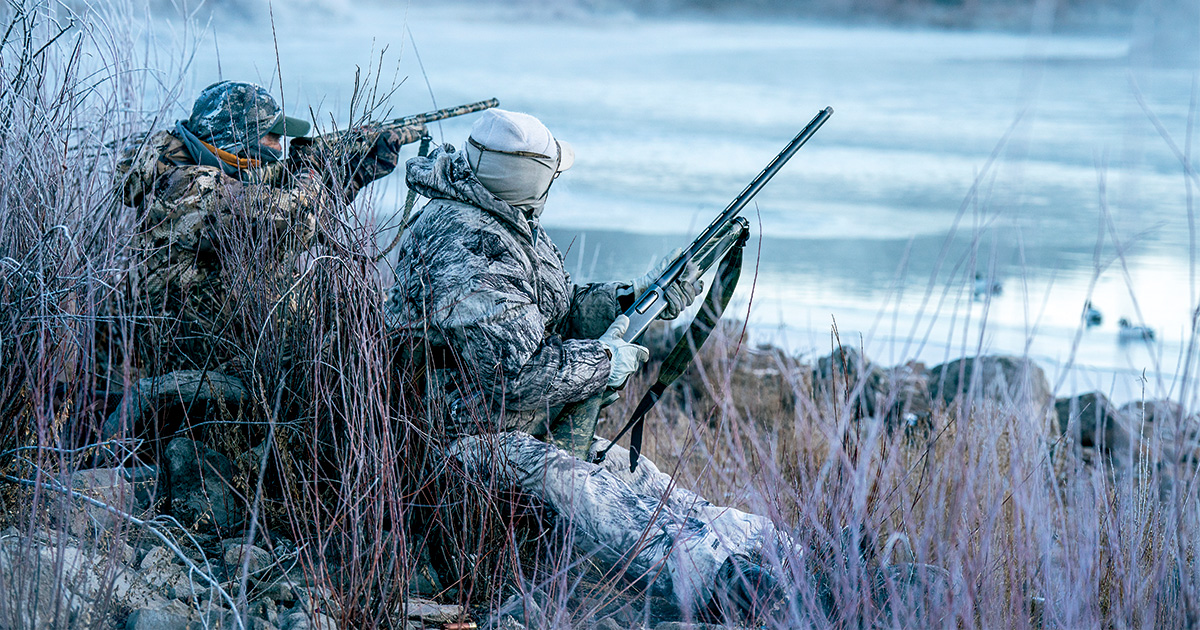 Hunters on riverbank, taking aim. Photo by Greg Sweeney