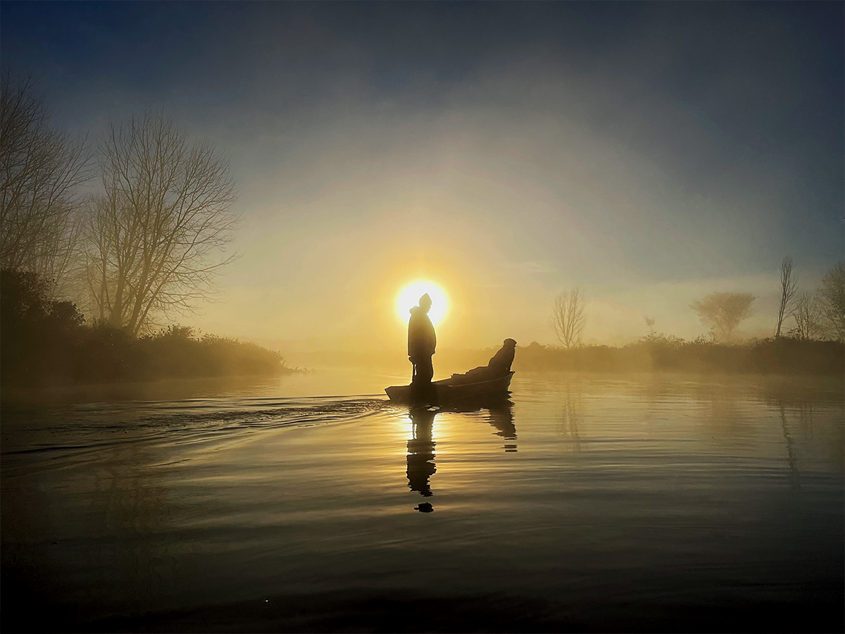 Hunter and retriever in a boat. By Nathan Howe